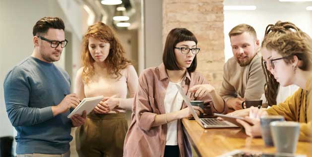 A group of men and women discuss something in a corporate setting