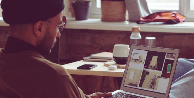 Man sits at a desk with a laptop on his legs as he writes